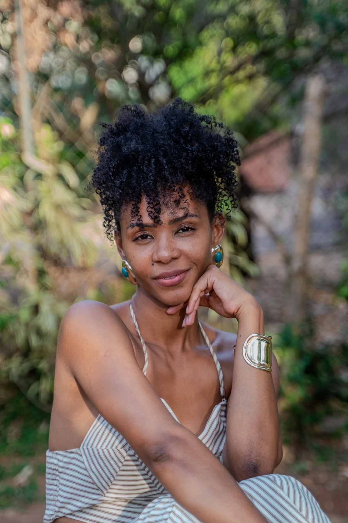 Érika Ramos sentada entre árvores, com a mão junto ao rosto